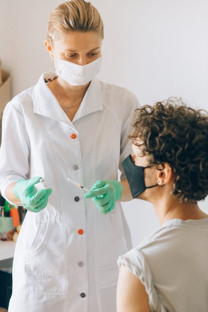 Doctor in mask administering a vaccine to patient in a clinic setting.